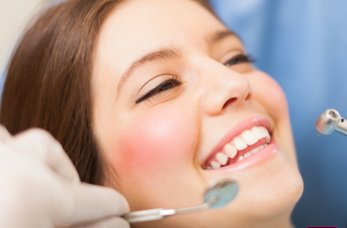 Close up of a young female adult smiling in the dentist's chair.
